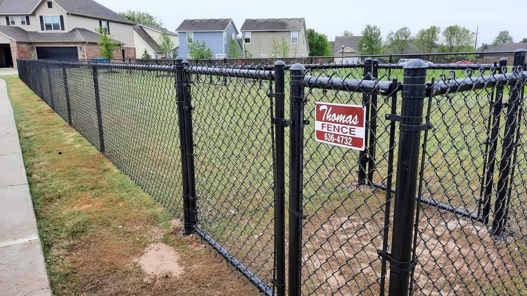 Black vinyl-coated chain link fence installed by Thomas Fence in Rogers, Arkansas